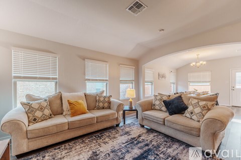 A living room with a beige couch and a patterned rug.