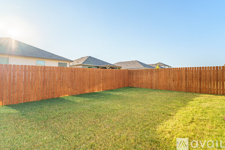A backyard with a wooden fence and green grass.