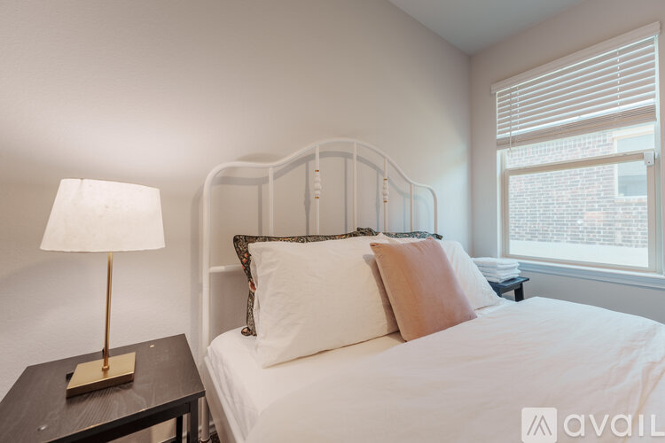 A bedroom with a white bed and a lamp on a side table.