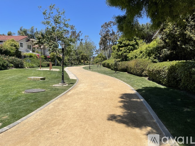 A pathway in a park with a lamp post on the left side.
