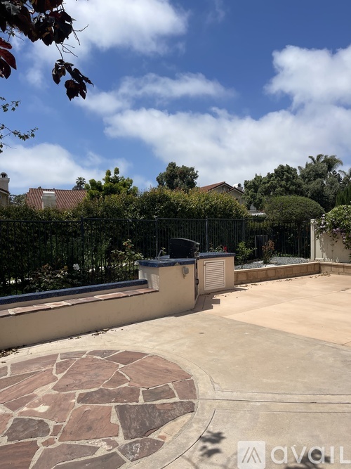 A backyard with a stone patio and a fence.