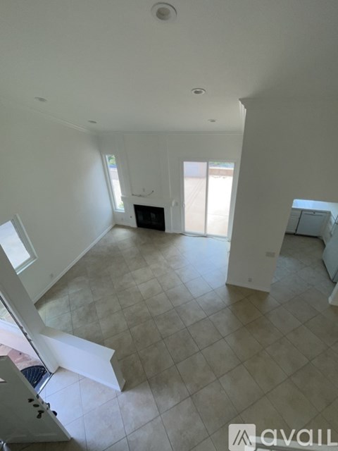 A large empty room with tiled flooring and a staircase leading to another level.