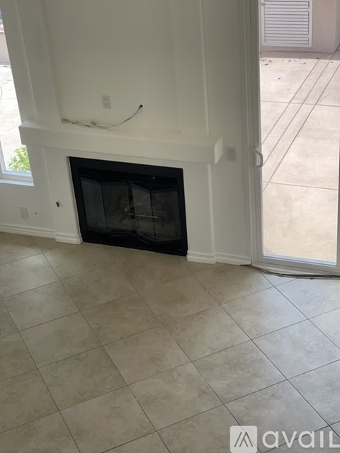 A tiled floor leads to a fireplace in a white room.