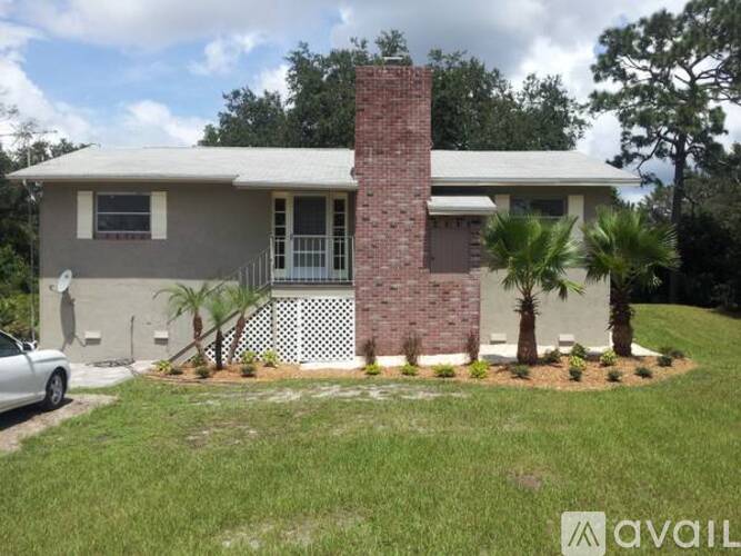 A house with a brick chimney and a white fence.