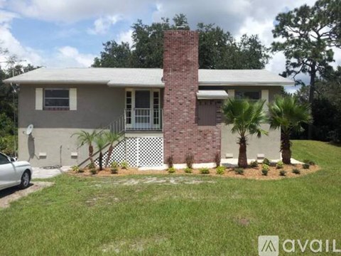 A house with a brick chimney and a white fence.