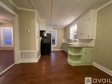 A kitchen area with a counter, cabinets, and a trash bin.