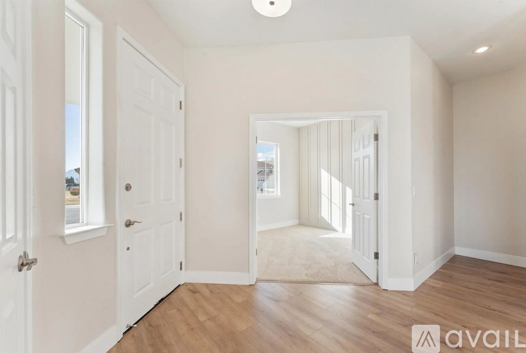 A spacious, empty room with white walls and wooden flooring.