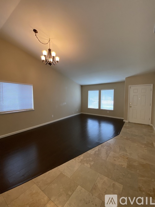 A room with a chandelier, tiled floor, and a door.