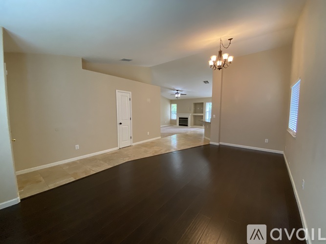 A spacious room with wooden floors and a chandelier.