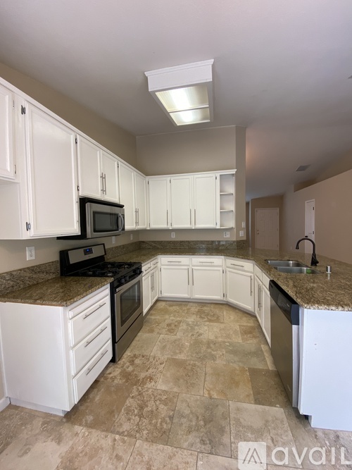 A kitchen with white cabinets and a granite countertop.