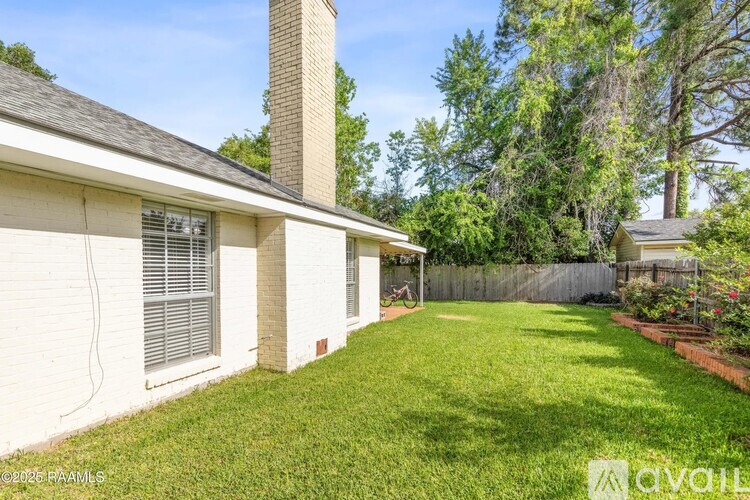A house with a white exterior and a chimney is surrounded by a green lawn.