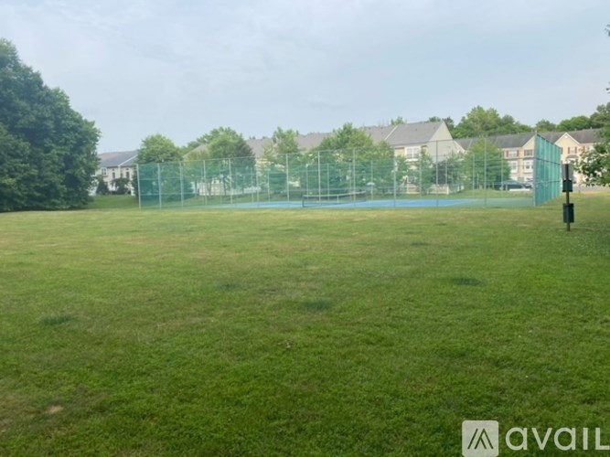 A grassy field with a fence and houses in the background.