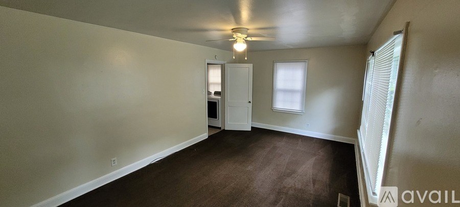 A room with a carpeted floor and a ceiling fan.