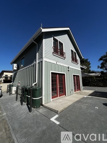 A grey building with a red door and windows.