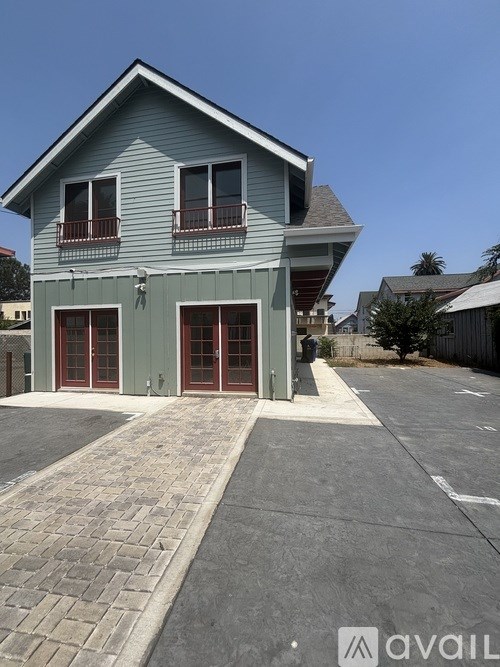 A two-story house with a grey exterior and red doors.