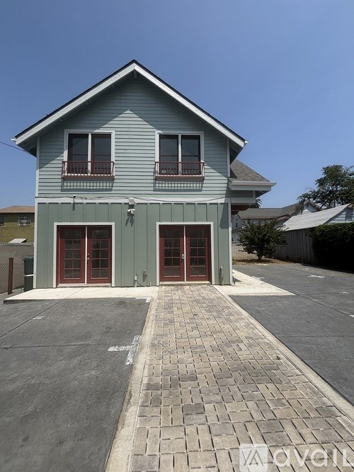 A blue house with a grey roof and a red door.