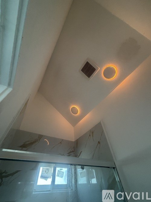 A ceiling with two circular lights and a window.