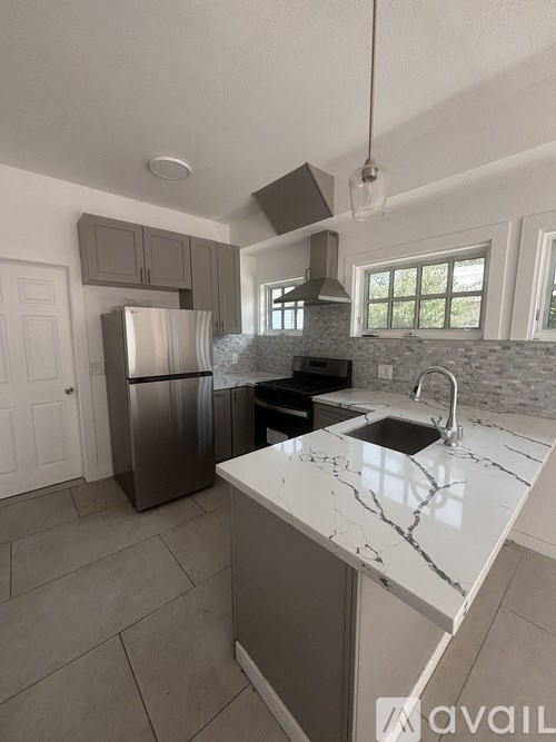 A kitchen with a marble countertop and a stainless steel refrigerator.