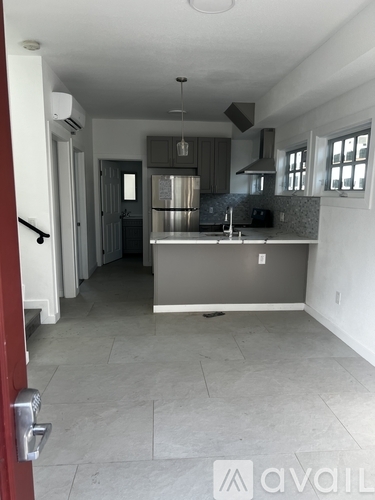 A kitchen with a refrigerator, sink, and stove top oven.
