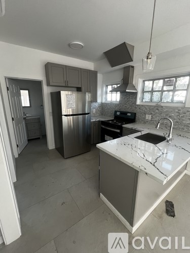 A kitchen with a marble countertop and a stainless steel refrigerator.