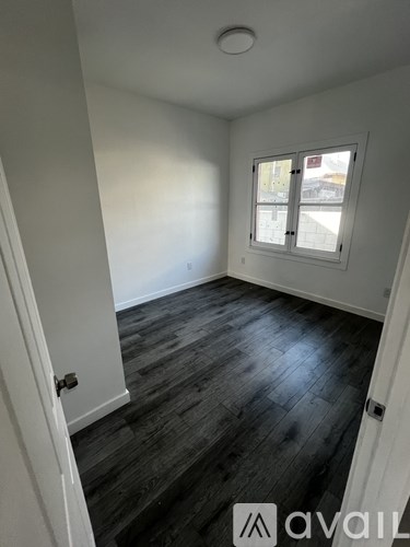 A room with a window and wooden flooring.