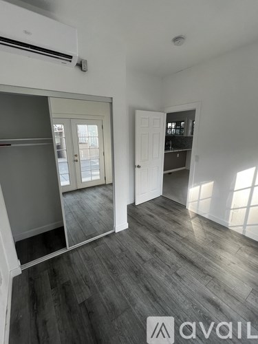 A room with a wooden floor and a white wall with a window.
