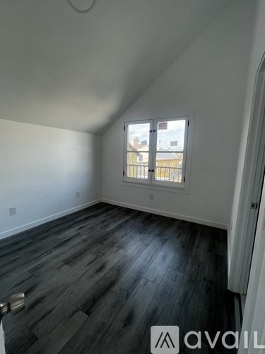 A room with a window and wooden flooring.