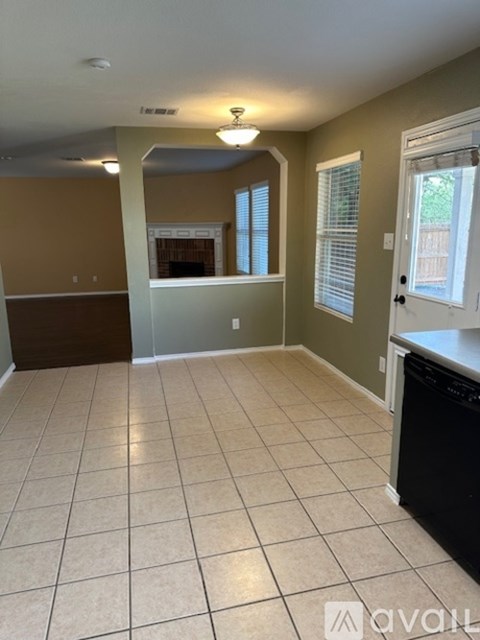 A kitchen with a black dishwasher and a tiled floor.
