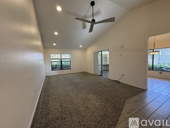 A spacious room with a ceiling fan and large windows.