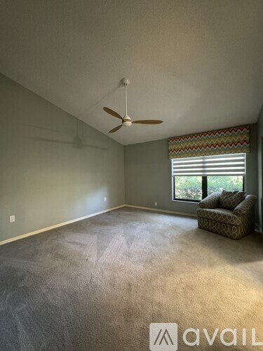 A room with a ceiling fan and a window with blinds.