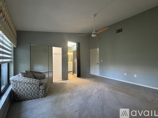 A spacious room with a ceiling fan and a large window with blinds.
