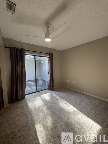 A room with a carpeted floor and a ceiling fan.