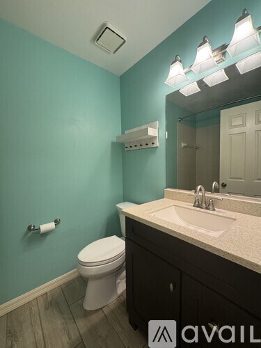 A bathroom with a toilet, sink, and mirror.