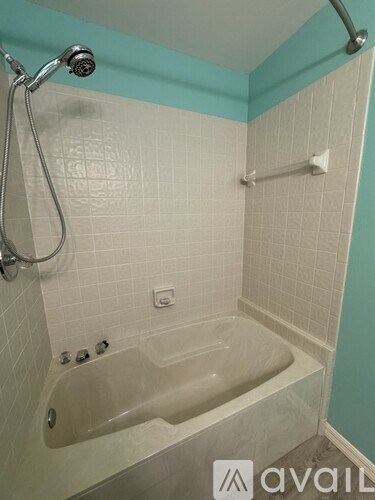 A bathroom with a white tub and a shower head.
