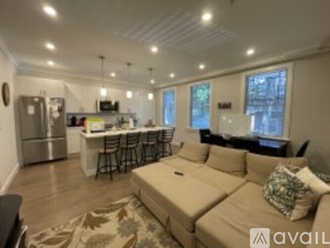 A living room with a couch and a kitchen area in the background.