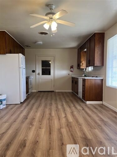 A kitchen with a white fridge and wooden floors.