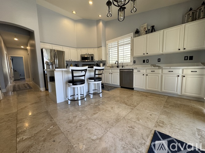 A kitchen with white cabinets and a marble floor.