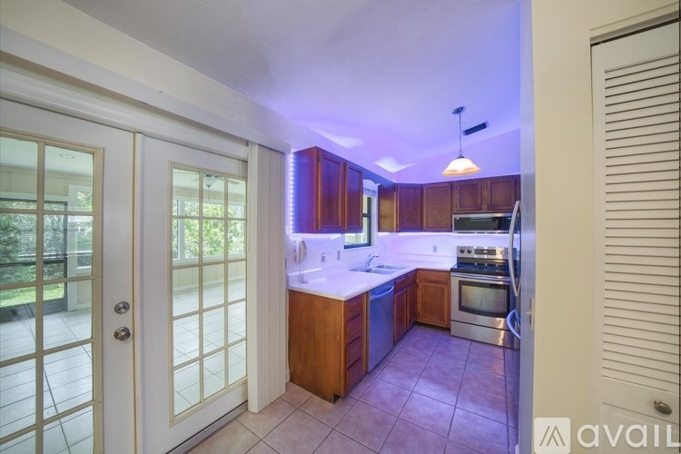 A living room with a brown couch, a grey rug, and a ceiling fan.