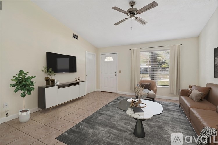 A living room with a ceiling fan, a flat screen TV, a couch, and a potted plant.
