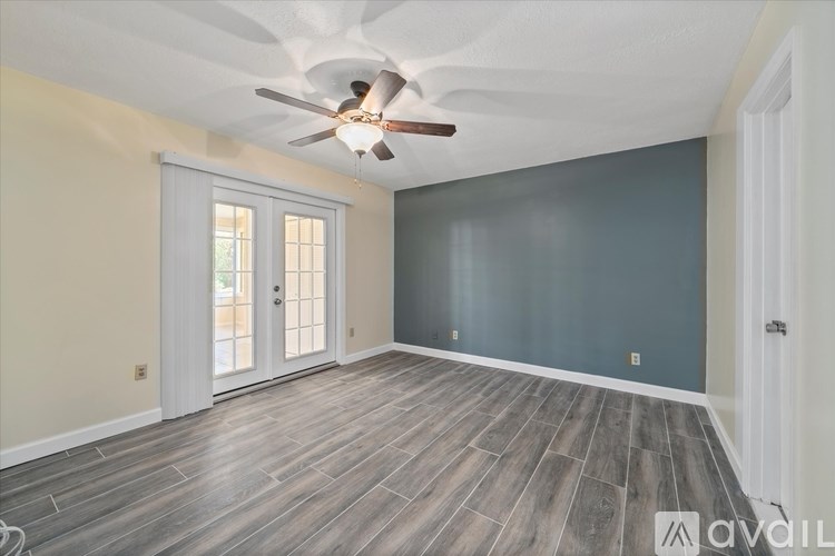 A room with a ceiling fan and sliding glass doors.