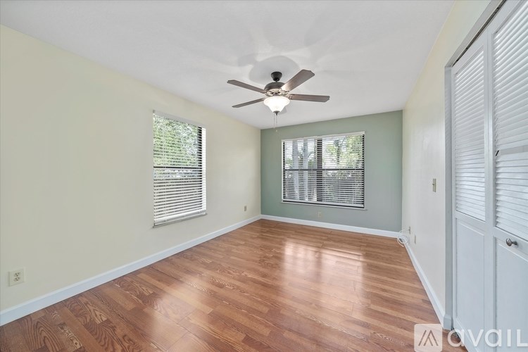 A room with a ceiling fan and wooden flooring.