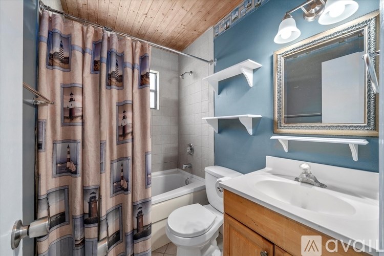 A bathroom with a white sink, toilet, and a shower curtain with a picture of a woman on it.