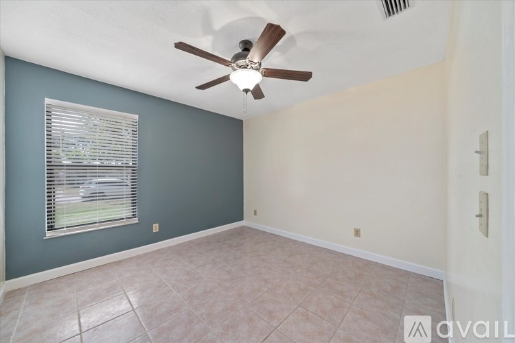 A room with a ceiling fan and a window with blinds.
