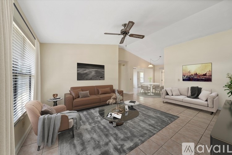 A living room with a brown couch, a grey rug, and a ceiling fan.