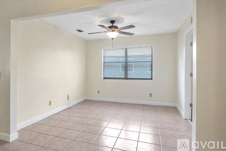 A room with a ceiling fan and a window with blinds.