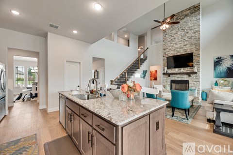 A modern kitchen with a stone fireplace and a living room area with a couch and a chair.