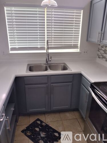 A kitchen with a sink and a window with blinds.