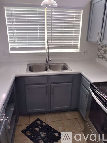 A kitchen with a sink and a window with blinds.