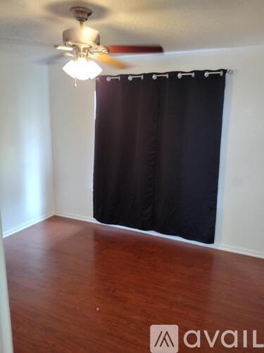 A room with a ceiling fan and a black curtain.