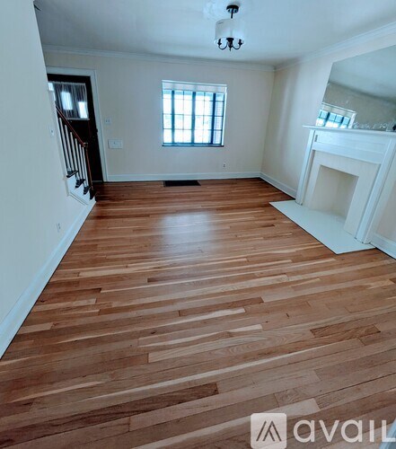 A room with wooden flooring and a fireplace.